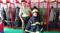 “我是小小消防員”主題活動，小朋友們在消防員叔叔的幫助下穿上消防衣。